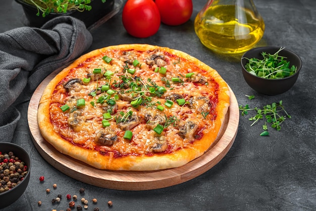 Domowa pizza z pieczarkami, serem, pomidorami i świeżymi ziołami na ciemnym tle