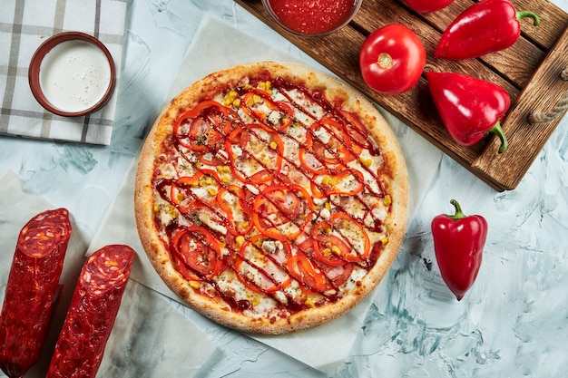 Domowa pizza z pieczonego mięsa z pomidorami, serem, kiełbasami, czerwonym sosem. Skład z chrupiącą pizzą, pomidorami .. Widok z góry