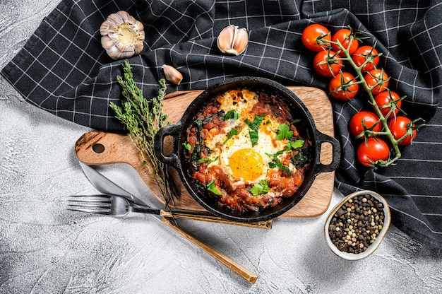 Domowa shakshuka, jajka sadzone, cebula, papryka, pomidory i natka pietruszki na patelni.