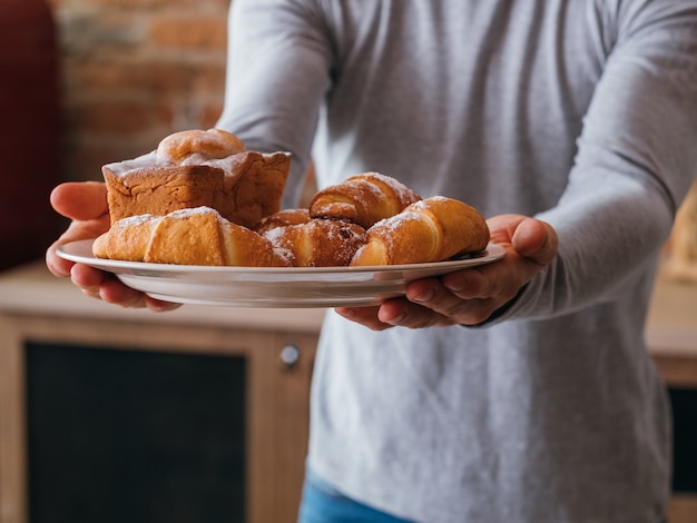 Domowa słodka piekarnia. Pyszne produkty deserowe. Człowiek z półmiskiem świeżych ciast i ciastek.