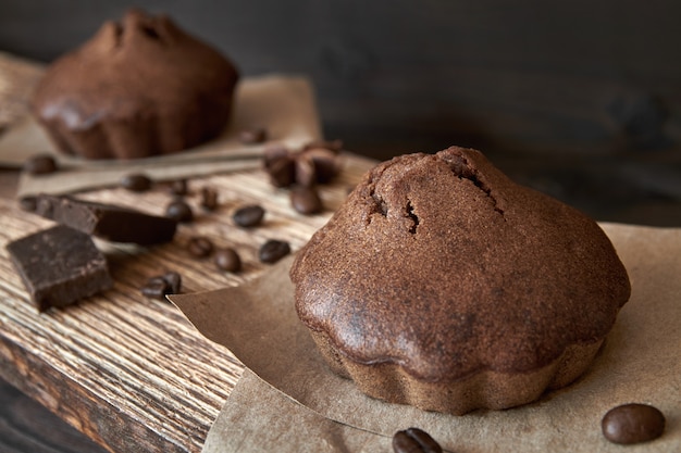 Domowe babeczki czekoladowe na desce z ziaren kawy i kawałków czekolady.