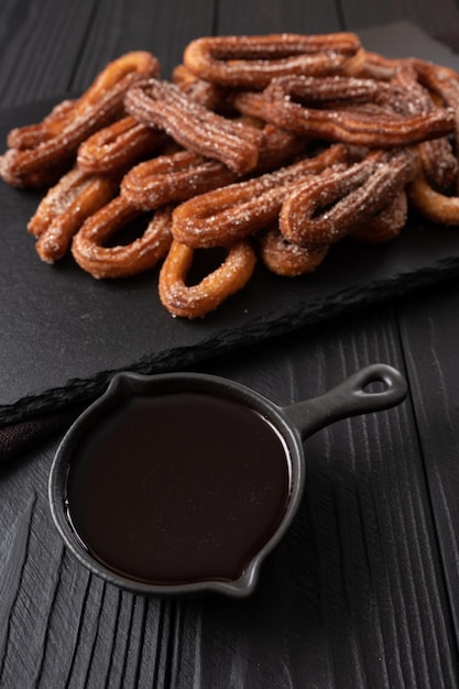 Domowe churros z czekoladą na ciemnym drewnianym rustykalnym tle