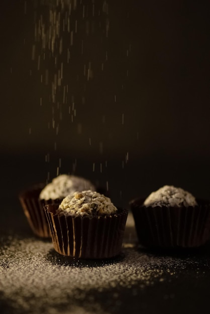 Domowe cukierki czekoladowe posypane cukrem pudrem na ciemnym tle