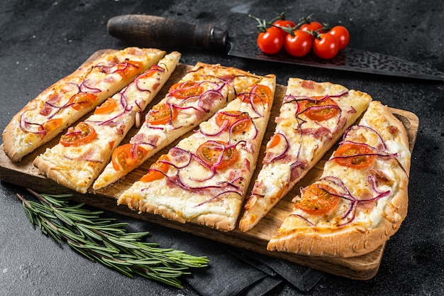 Domowe flammkuchen lub tarte flambee z serkiem, bekonem, pomidorem i cebulą Czarne tło Widok z góry