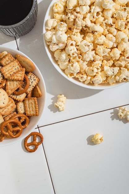 Domowe gadżety fast food miska z krakersami popcornowymi i ciasteczkami na białym stole