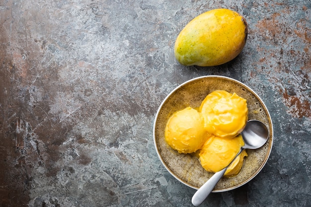 Domowe lody mango w miseczkach ze świeżymi owocami w kolorze ciemnoszarym