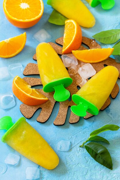 Domowe lody na lodzie z sokiem pomarańczowym na niebieskim tle z kamienia lub łupka