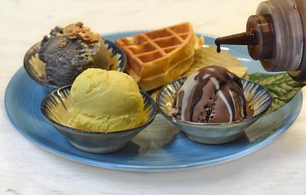 Domowe lody na niebieskim talerzu z polewą czekoladową