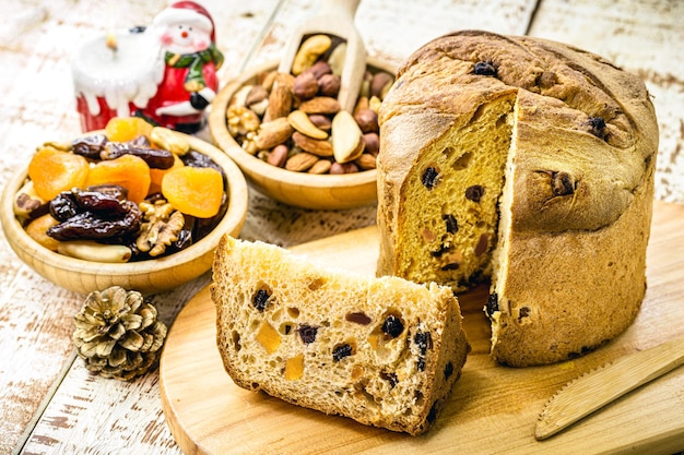 Zdjęcie domowe panettony na białym drewnianym stole, cieście lub pieczonym chlebie typowym dla brazylijskich i europejskich świąt bożego narodzenia, nadziewane owocami i orzechami