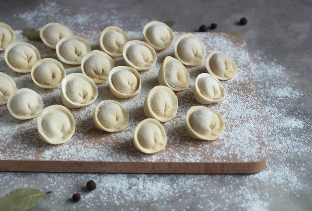 Domowe pierogi na desce do krojenia w rzędach z mąki pieprzowej i liścia laurowego