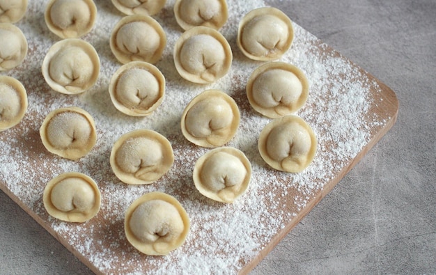 Domowe pierogi na desce do krojenia w rzędach zbliżenia mąki