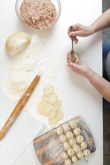 Domowe pierogi w kuchni bez ozdób. robienie pierogów z mieloną wieprzowiną, wołowiną i kurczakiem