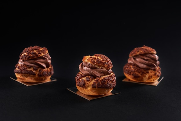 Domowe profiteroles z kremem czekoladowym na czarnym tle.