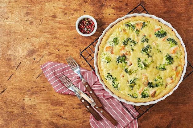 Domowe quiche z czerwoną rybą, łososiem, brokułami i serem na drewnianym tle. Widok z góry.