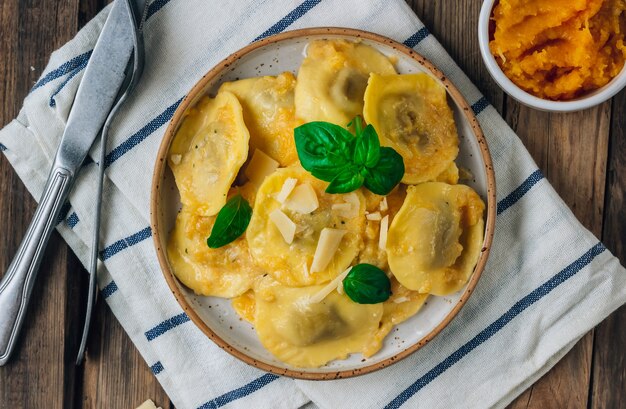 Domowe ravioli z dynią z sosem i bsilem na rustykalne drewniane tła. Jesienna koncepcja żywności.