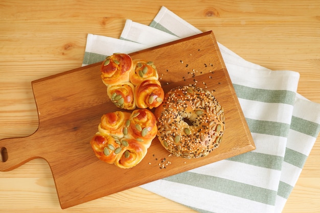 Domowe różne rodzaje pieczywa na drewnianej tacy z ściereczką kuchenną