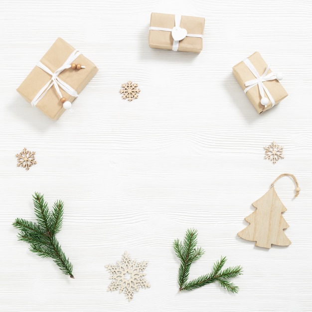 Domowe upominki, pudełka na prezenty świąteczne zawinięte w papier kraft, naturalne gałązki jodły, płatki śniegu