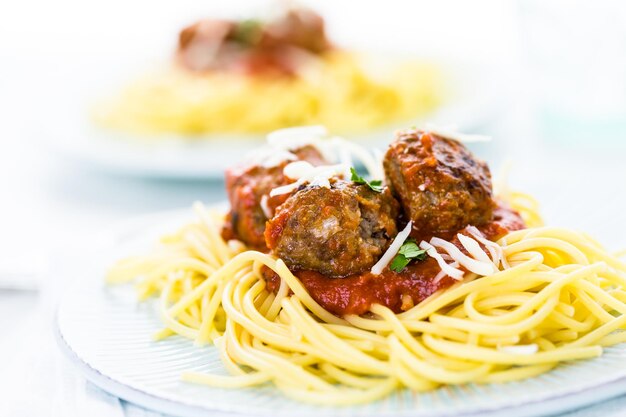 Domowe włoskie klopsiki przybrane kolendrą i parmezanem na spaghetti na kolację.