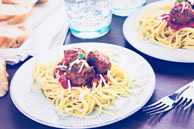 Domowe włoskie klopsiki przybrane kolendrą i parmezanem na spaghetti na kolację.