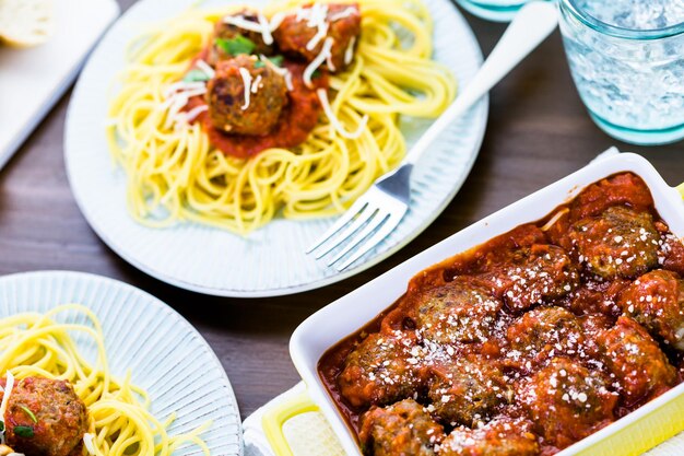 Domowe włoskie klopsiki przybrane kolendrą i parmezanem na spaghetti na kolację.