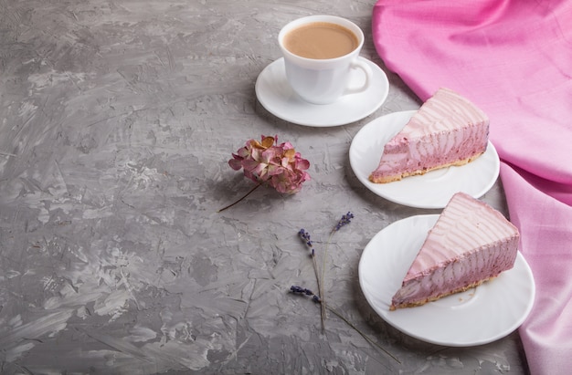 Domowej roboty różowy sernik z filiżanką kawy na szarym betonowym tle. widok z boku, kopia przestrzeń.