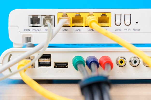 Zdjęcie domowy bezprzewodowy router z ethernetów kablami czopował wewnątrz na błękitnym tle, zbliżenie