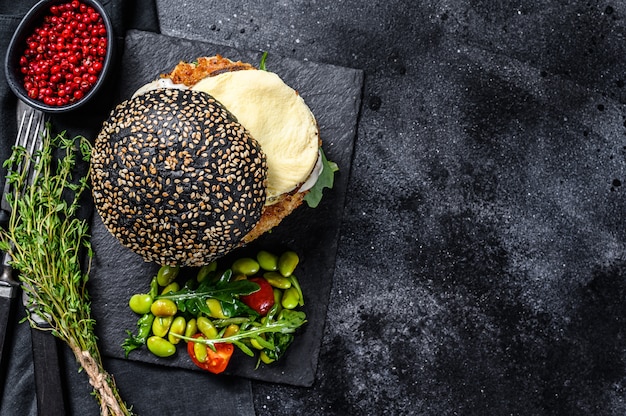 Domowy burger rzemieślniczy z czarną bułką, jajecznicą i rukolą.
