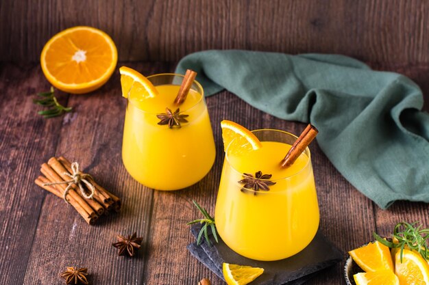 Domowy gorący grog pomarańczowy z kardamonem i cynamonem w szklankach na stole