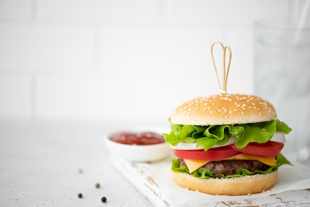 Domowy hamburger z keczupem i przyprawami na białej tablicy
