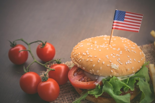 Zdjęcie domowy hamburger z świeżymi warzywami, frytki, wołowina, cebula, pomidory, amerykańskie flagi.