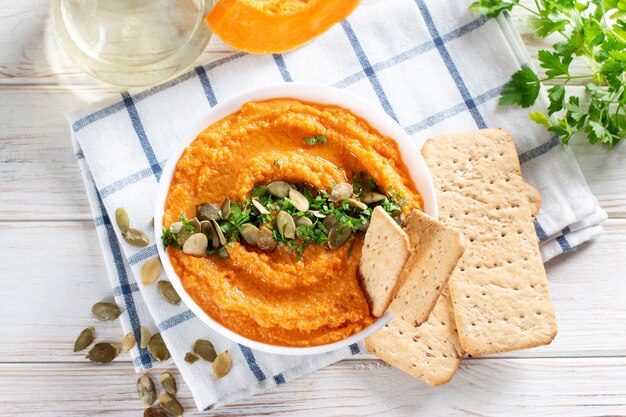 Domowy hummus dyniowy z czosnkiem, cytryną i pieprzem zbliżenie na talerzu na stole. Poziomy widok z góry z góry