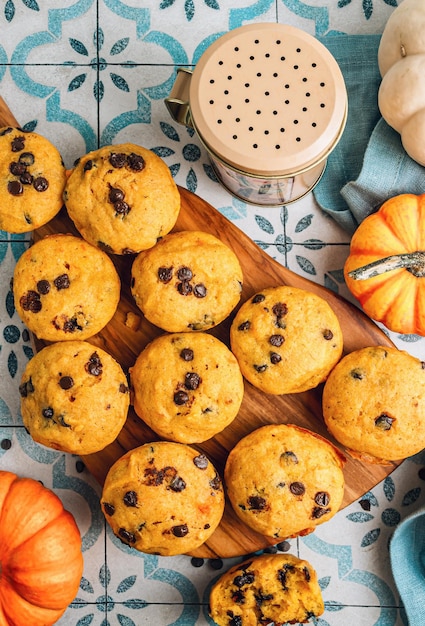 Zdjęcie domowy jesienny pumpkin muffin z czekoladowymi czapkami na niebieskim tle z płytek