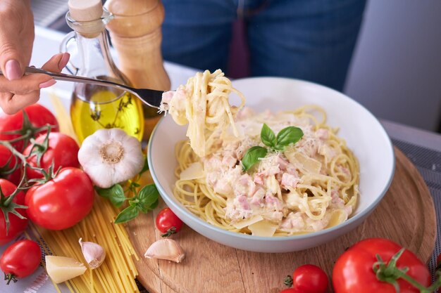 Domowy makaron carbonara ze świeżą bazylią i parmezanem w naczyniu ceramicznym