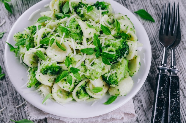 Zdjęcie domowy makaron orecchiette z brokułami, parmezanem i bazylią na drewnianym stole