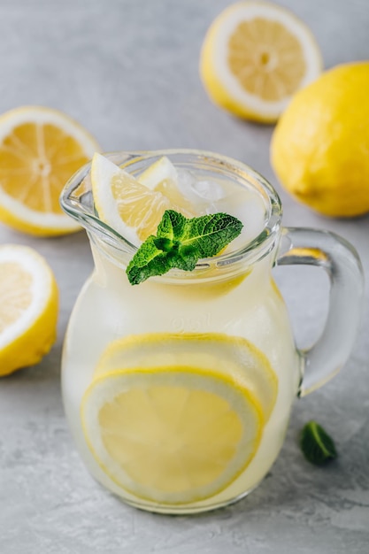 Domowy orzeźwiający napój letnia lemoniada z plasterkami cytryny, imbirem, miętą i lodem