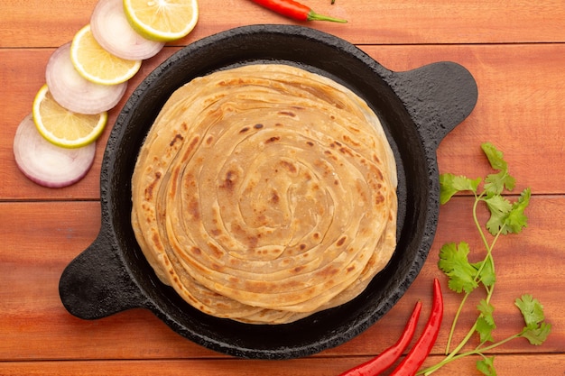 Domowy placek parotta lub paratha, wypiekany z mąki pszennej ułożonej w żeliwnej patelni