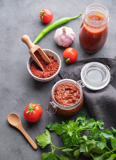 Domowy sos pomidorowy do pizzy lub makaronu w słoiku na ciemnym tle ze świeżymi warzywami, ziołami i przyprawami Koncepcja klasycznej kuchni włoskiej