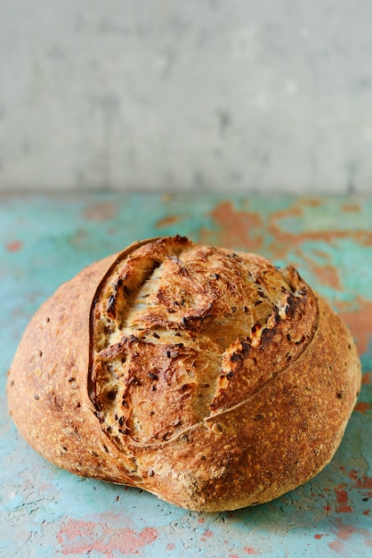 Domowy Świeżo Pieczony Chleb Wiejski wykonany z mąki pszennej i pełnoziarnistej na szaro-niebieskiej ścianie. Francuski Świeżo upieczony chleb. Krojenie domowego chleba