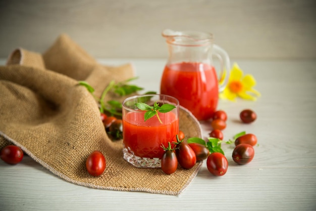 Domowy świeżo wyciśnięty sok pomidorowy z miąższem w szklanej karafce na drewnianym stole