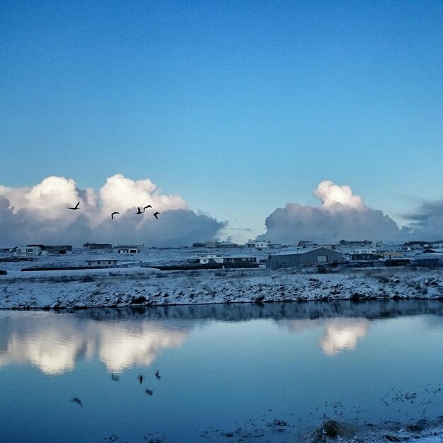 Zdjęcie domy na śnieżnym polu przy rzece na tle niebieskiego nieba