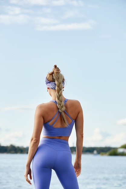 Dopasowana sportowa i wysportowana młoda kobieta Piękna dziewczyna w sportowej odzieży gotowa do rozpoczęcia treningu na niebieskim niebie