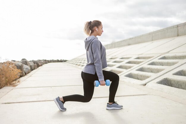 Dopasowana szczupła sportowa kobieta trenuje mięśnie nóg z hantlami na świeżym powietrzu Zdrowy styl życia Fitness kulturystyka