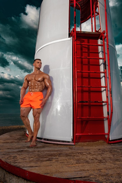 Zdjęcie dopasuj kulturystę sportowca na plaży atrakcyjne młodych ratownik mężczyzna w pobliżu wieży obserwacyjnej na plaży
