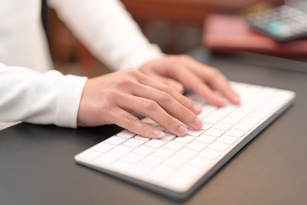 Doradca finansowy pisania na klawiaturze, siedząc w biurze i pracy na komputerze