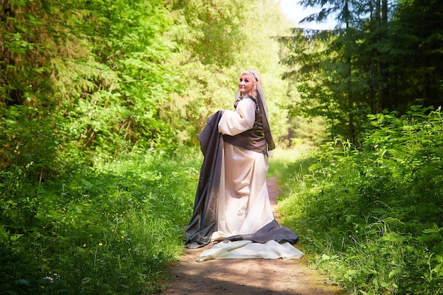 Dorosła dojrzała kobieta w zielonej długiej sukience w leśnej sesji zdjęciowej w stylu dryady i królowej