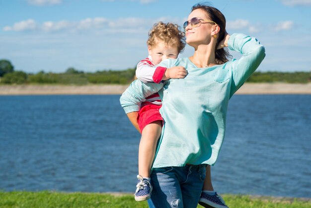 Dorosła kobieta mama z synkiem małego chłopca bawi się w parku Mama trzyma syna na ramionach