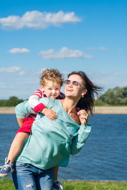 Dorosła kobieta mama z synkiem małego chłopca bawi się w parku Mama trzyma syna na ramionach