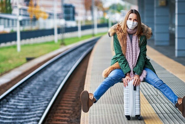 Zdjęcie dorosła kobieta na dworcu kolejowym w maskach z powodu ograniczeń covid-19