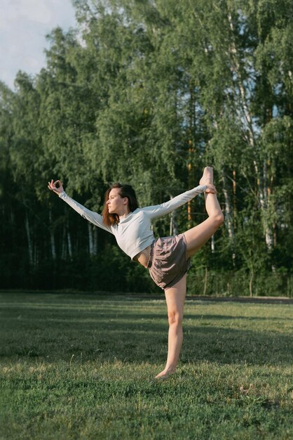 Zdjęcie dorosła kobieta praktykująca jogę na zewnątrz w crop top i lnianych koszulach