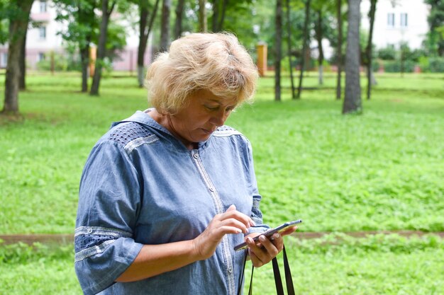dorosła kobieta w parku rozmawia przez telefon kobieta w wieku komunikuje się online